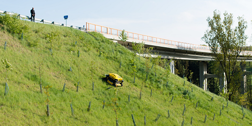 Spider mower on slope unmaintained area with operator at top of hill